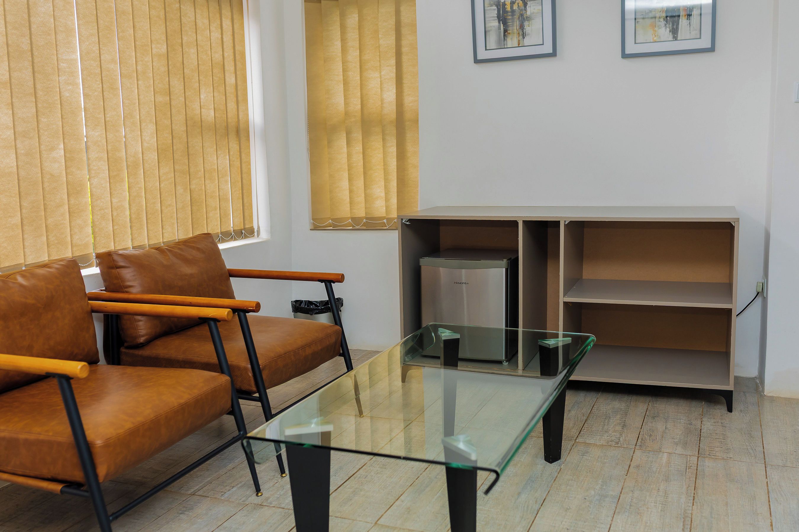 Ein Wohnzimmer mit einem braunen Ledersofa, einem Glastisch und einer weißen Schrankwand mit Regalen.