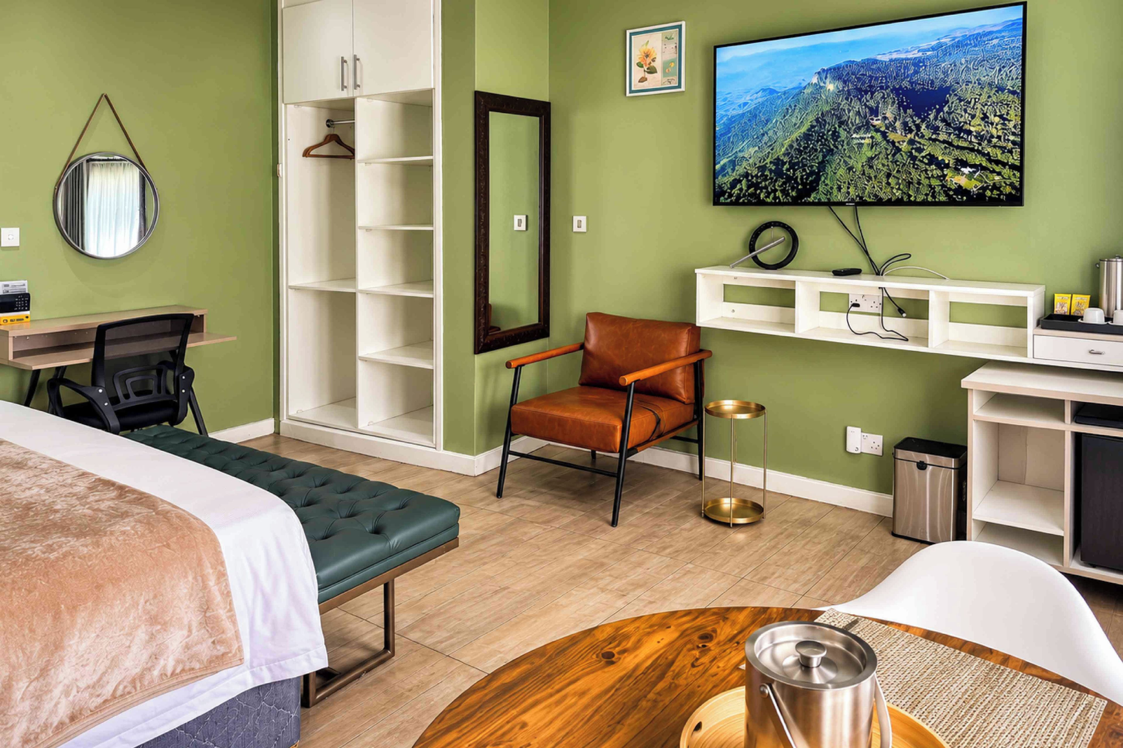 Quarto de hotel com cama, escrivaninha, cadeira, televisão e vista para uma paisagem montanhosa.