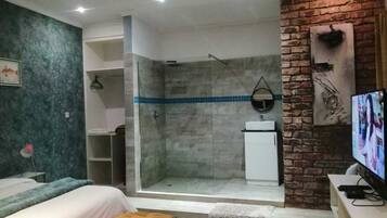 Un baño moderno con ducha, lavamanos y televisión.