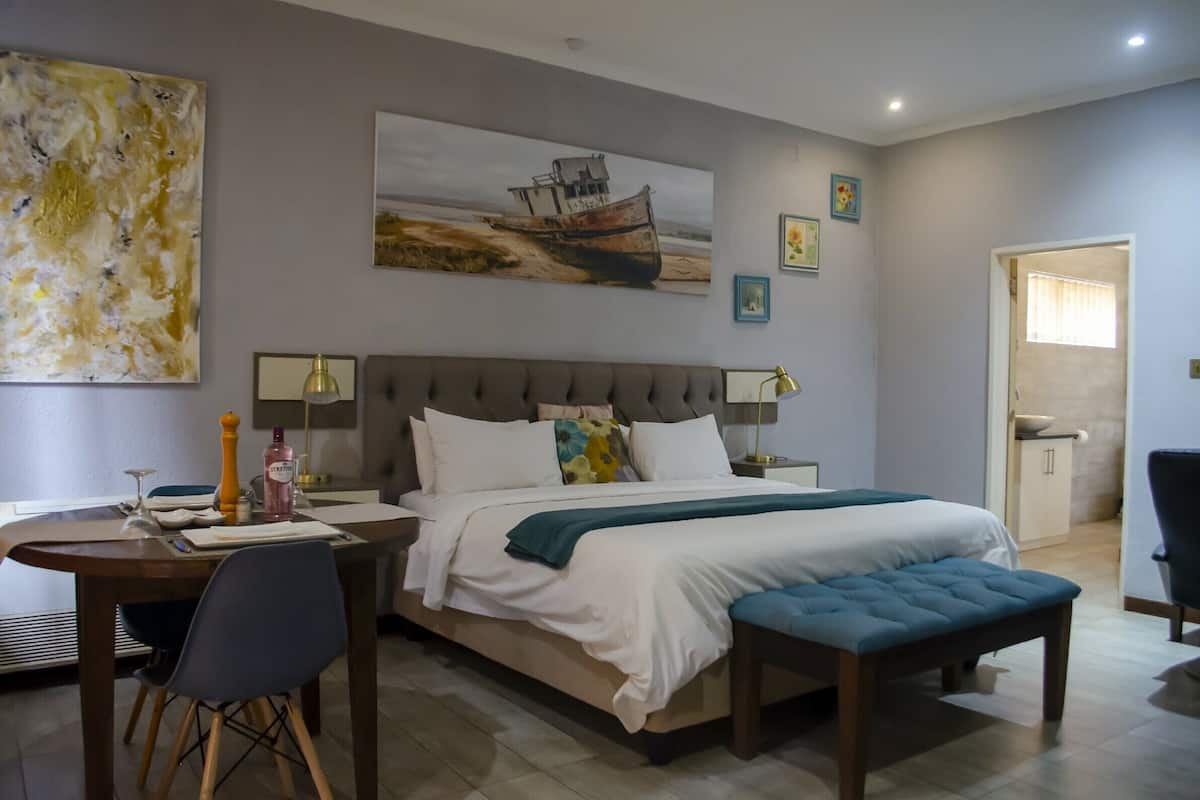 Quarto com cama, mesas de cabeceira, escrivaninha e cadeira.