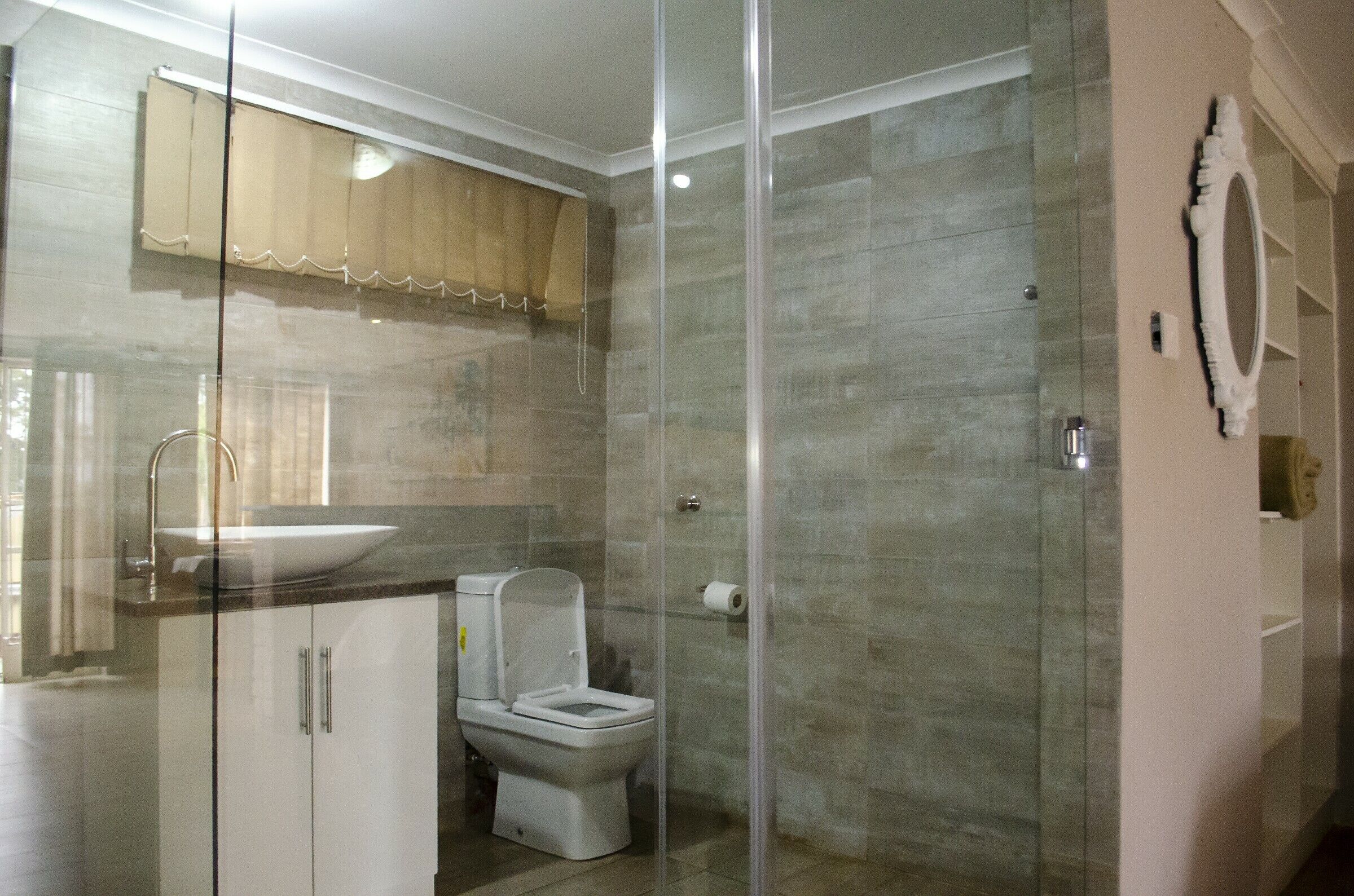 A modern bathroom with a glass shower enclosure, a toilet, and a sink.