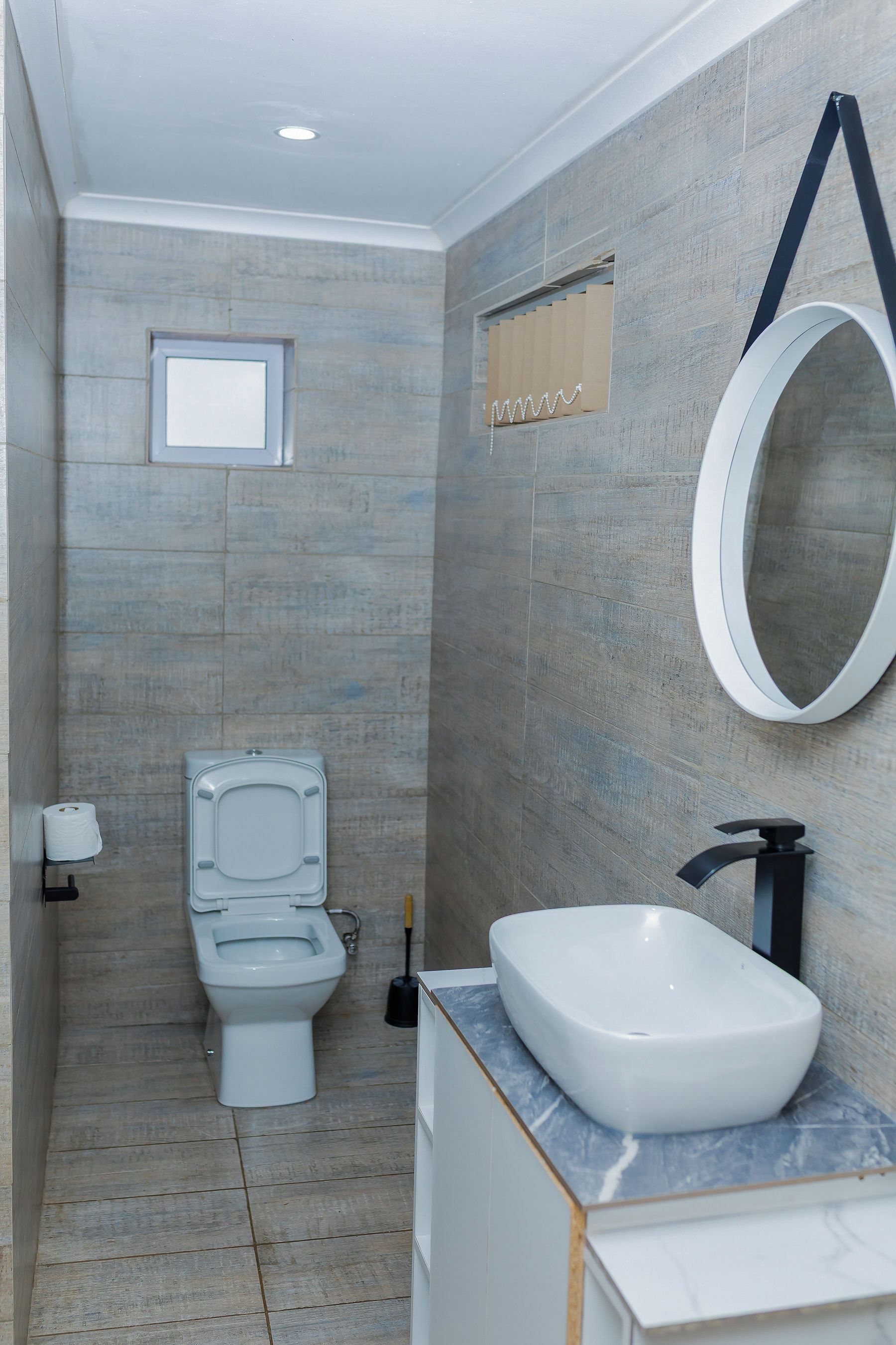 A bathroom with a toilet, a sink, and a mirror.