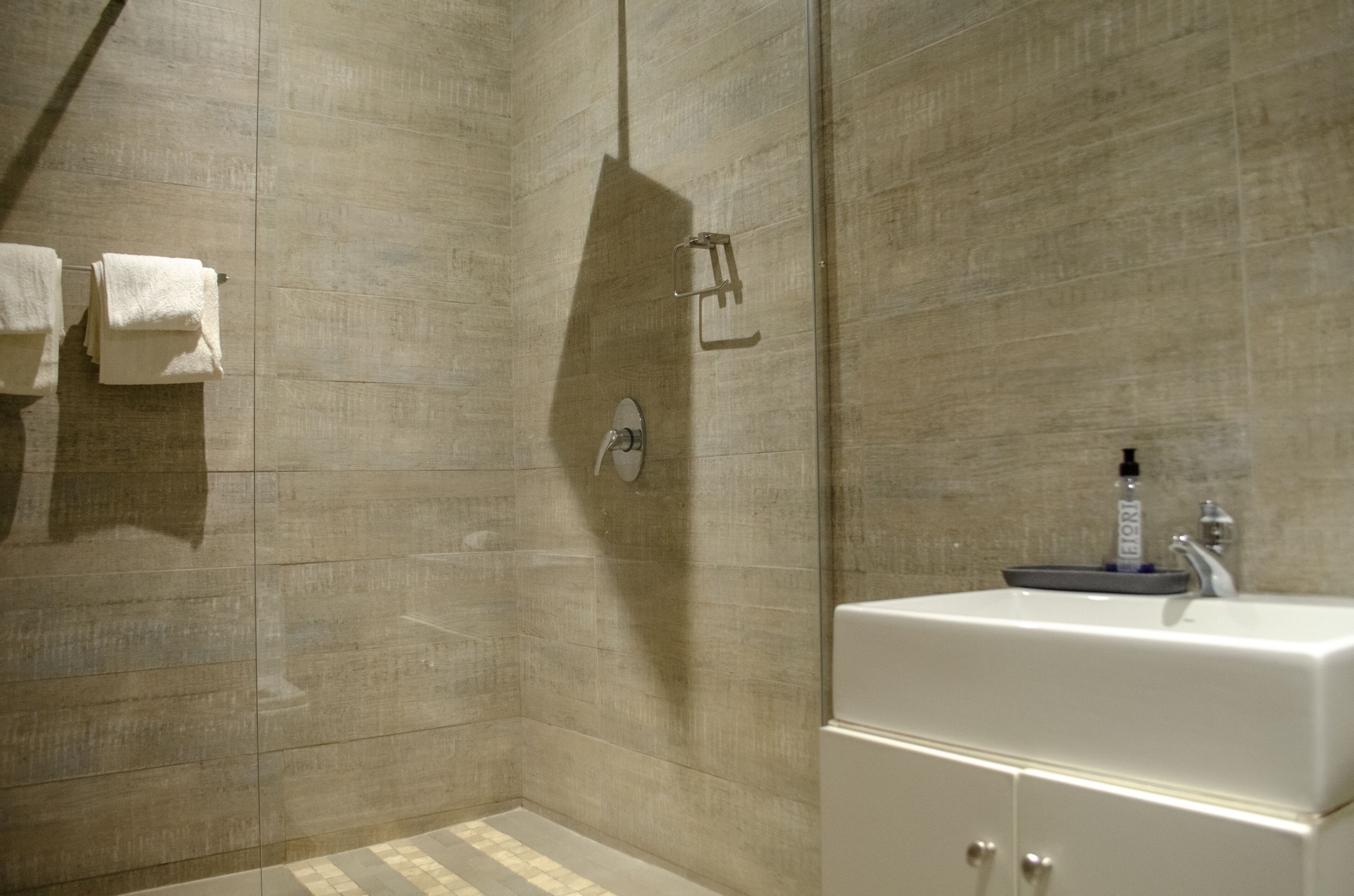 Une salle de bain avec une douche, un lavabo et un porte-serviettes.