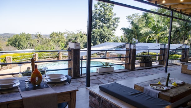 An outdoor dining area with a view of a pool and greenery. - The Hilltop Guesthouse (Harare)