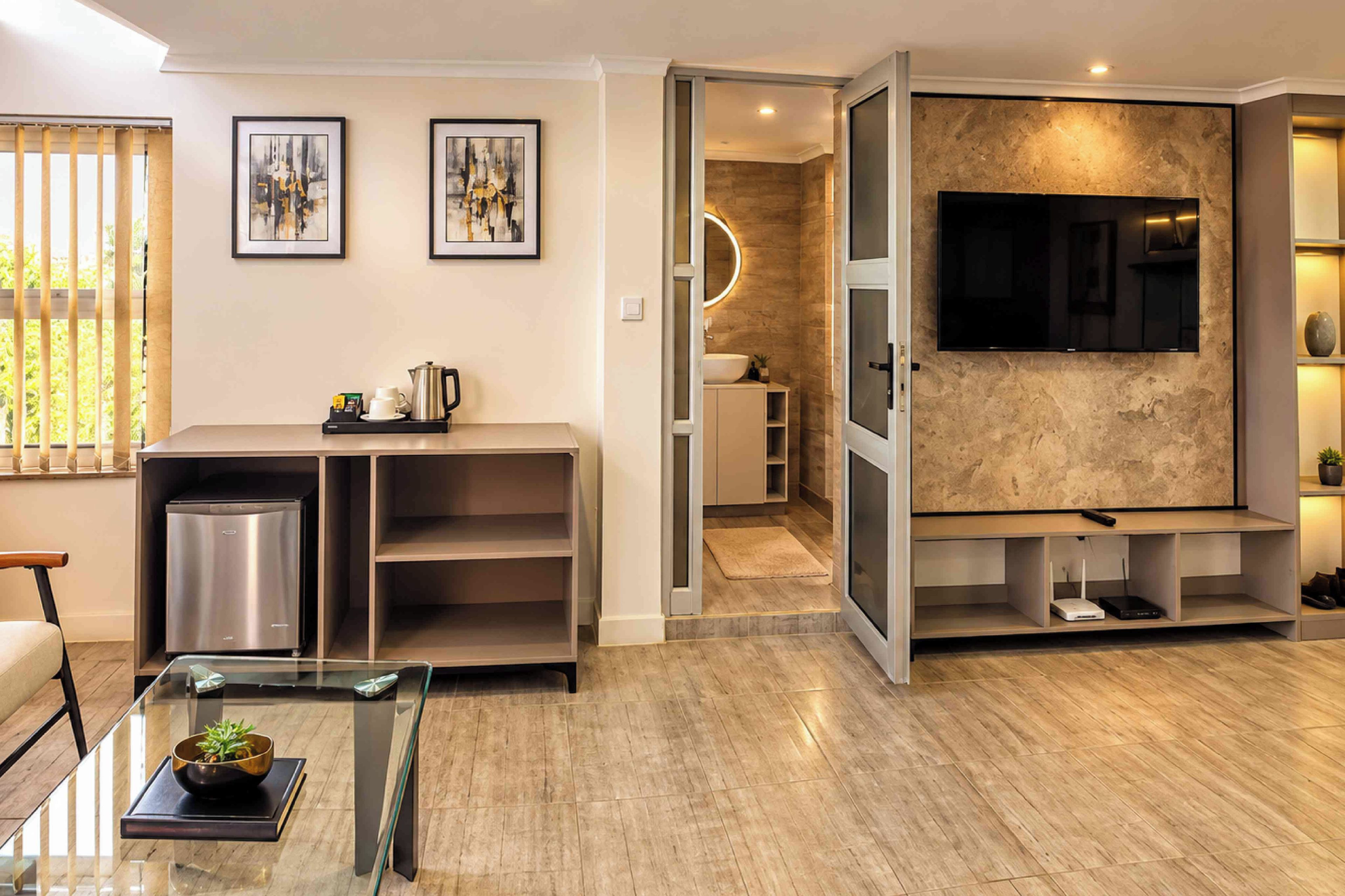 Una sala de estar moderna con un televisor de pantalla plana, una cafetera y un comedor con mesa de vidrio.