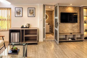 Una sala de estar moderna con un televisor de pantalla plana, una cafetera y un comedor con mesa de vidrio.