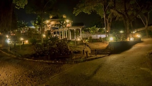 A well-lit gazebo-style building surrounded by trees and a paved pathway. - The Hilltop Guesthouse (Harare)