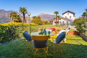 Une terrasse avec une table et des chaises, une vue sur les montagnes et une maison en arrière-plan.