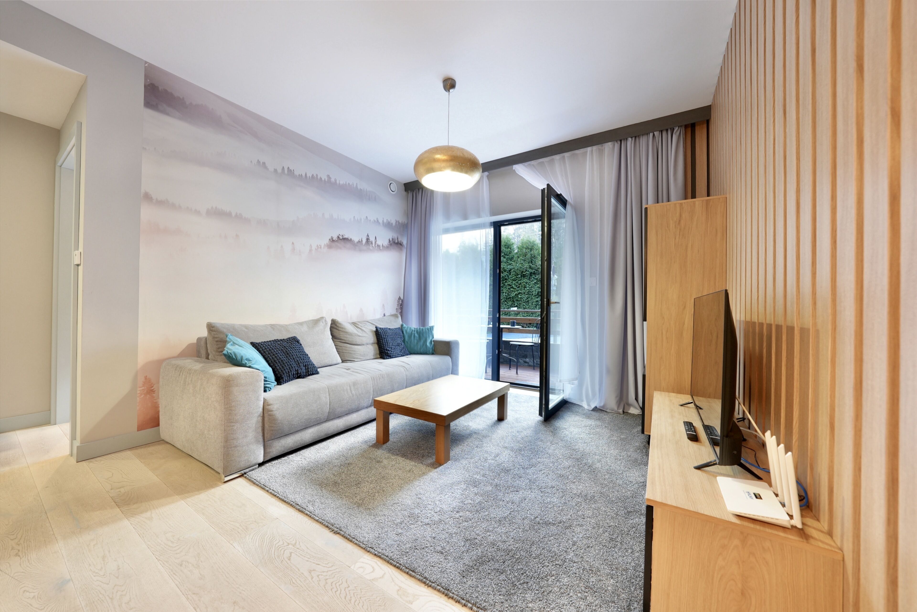 A modern living room with a sofa, coffee table, and a TV on a wooden stand.
