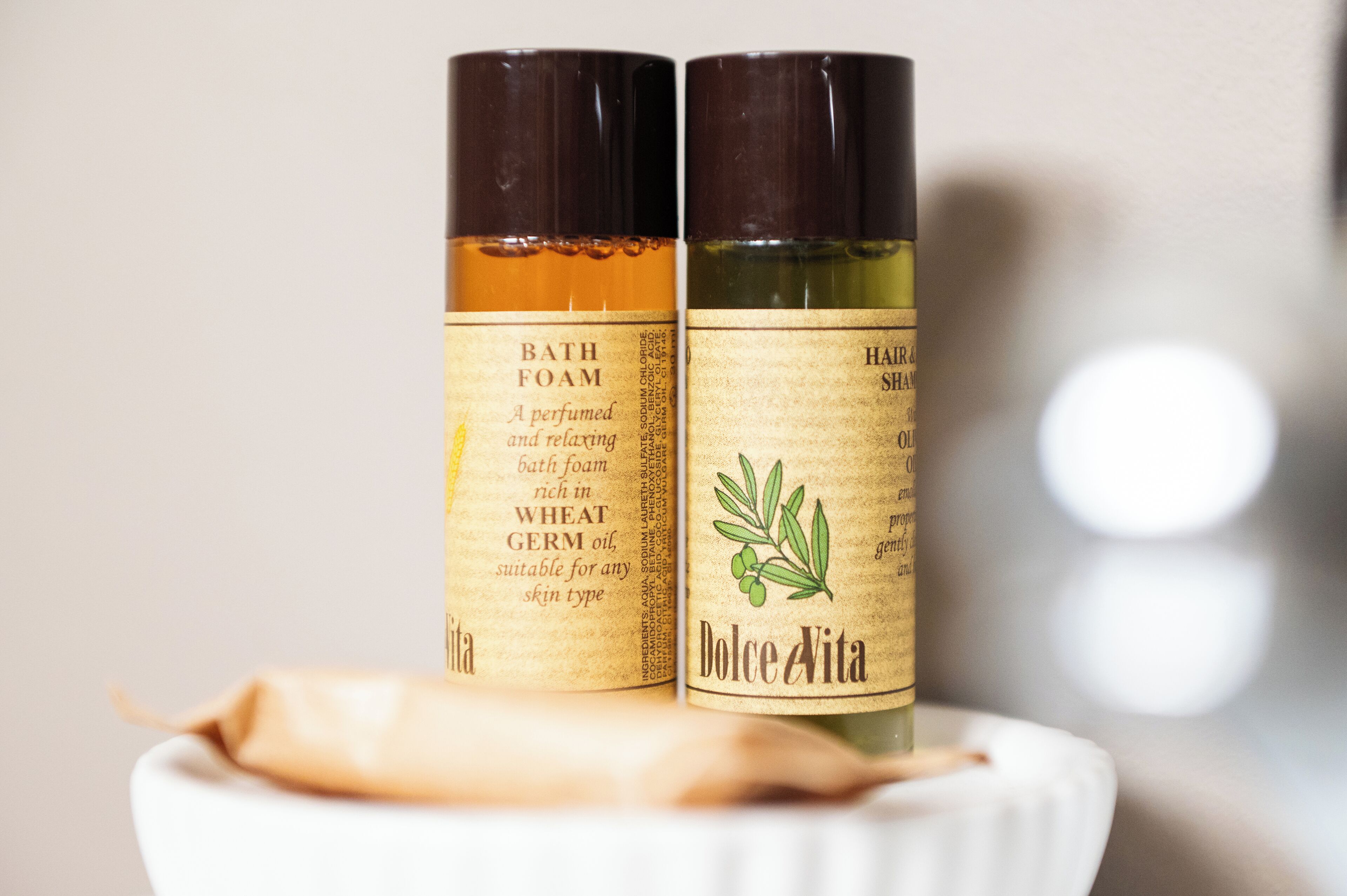 Two bottles of bath foam and hair spray on a white surface.