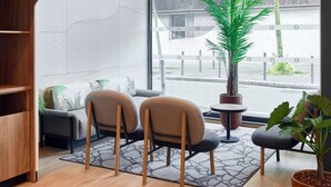 A modern interior with a sofa, two chairs, a small table, a potted plant, and a patterned rug. - B&B Hotel Paris Clichy-Sous-Bois (Clichy-Sous-Bois)