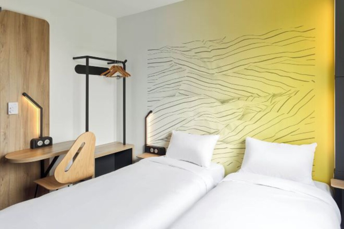 Ein modernes Hotelzimmer mit Bett, Nachttischen, einem Schreibtisch und einer Wand mit einem einzigartigen strukturierten Design.