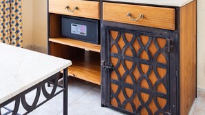 Quarto com televisão em um armário, cortina estampada e uma obra de arte emoldurada na parede.