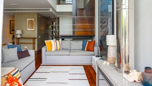 A modern living room with a grey sofa, striped rug, and a staircase leading to an upper level. - Troia Beach House With Pool (Grandola)