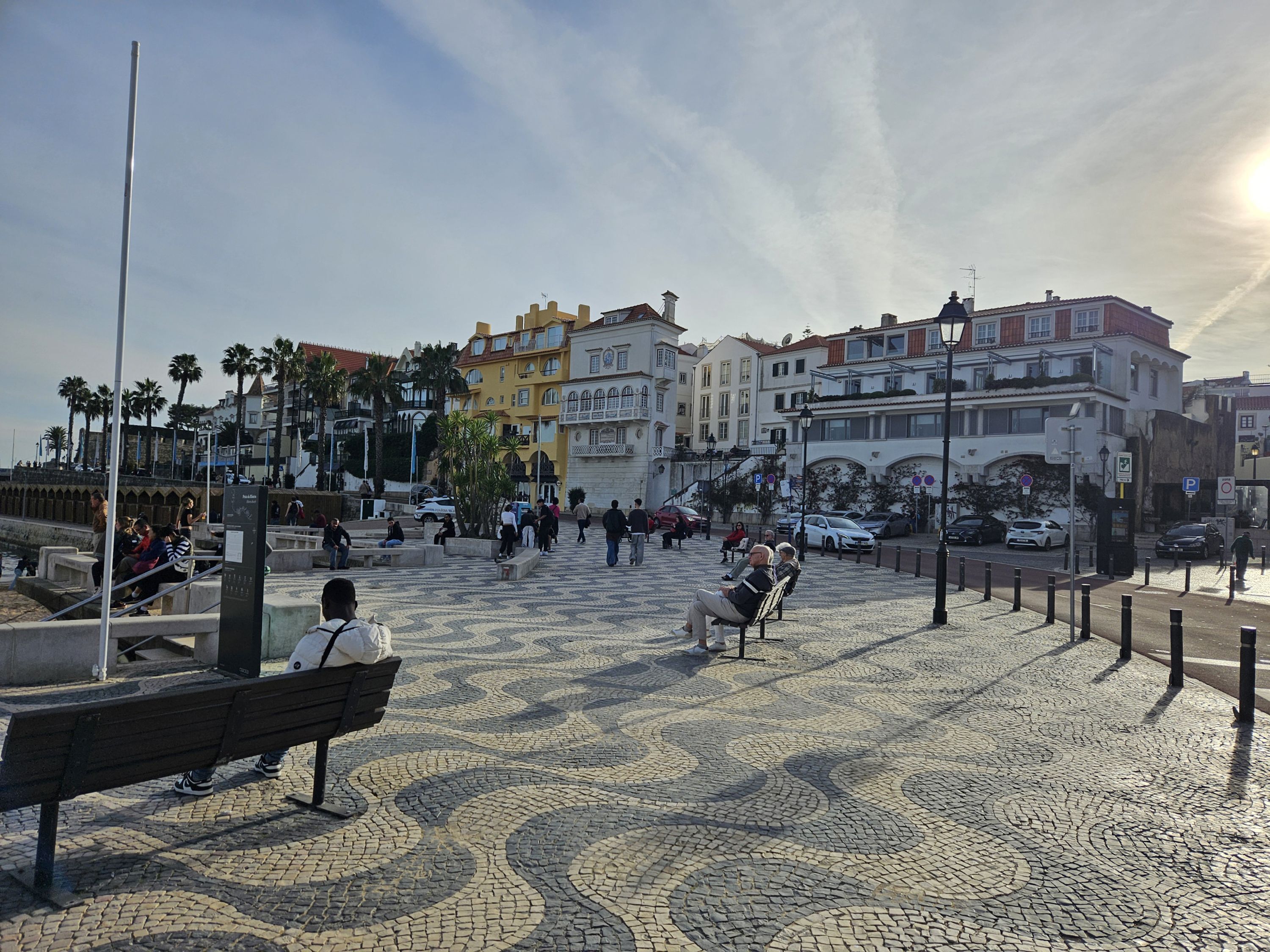 Ein gepflasterter öffentlicher Platz mit Bänken, einem Brunnen und Gebäuden im Hintergrund.