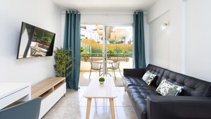 A modern living room with a sofa, a coffee table, and a TV mounted on the wall. - COSTA ADEJE BEACH & SUN 2 (Costa Adeje)