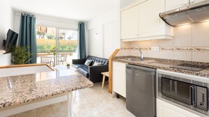 A modern kitchen with granite countertops, stainless steel appliances, and a view of a balcony with outdoor furniture. - COSTA ADEJE BEACH & SUN 2 (Costa Adeje)