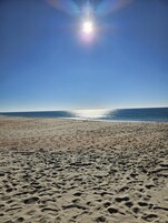 Una playa con cielo despejado y el sol brillando.