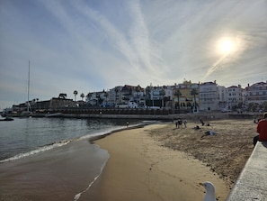 A beach with a stone wall, a clear sky, and buildings in the background. - Historic Center Cascais Bolina 1 (Cascais)