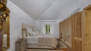 A bedroom with a bed, bedside table, mirror, wardrobe, and a window with curtains. - Almancil Seaview Countrystyle Charm Villa (Loulé)