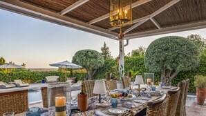An outdoor dining area with wicker furniture, a pool, and a view of the landscape. - Almancil Seaview Countrystyle Charm Villa (Loulé)