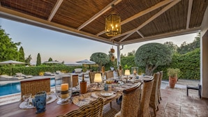 An outdoor dining area with wicker furniture, a pool, and a view of the landscape. - Almancil Seaview Countrystyle Charm Villa (Loulé)