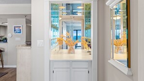 A kitchen with a white countertop, a vase with dried plants, and a glass door leading to a balcony. - SD 410: Seaside Summit - Watch the Sun Sink into the Gorgeous Gulf! (Fort Walton Beach)