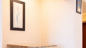 Eine Sitzecke mit einer Bank, einem gerahmten Bild an der Wand und einer Tür im Hintergrund.