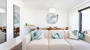 A modern living room with a beige sofa, a dining area with wooden furniture, and a large mirror on the wall. - Marvelous home with private pool (San Miguel de Abona)