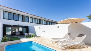 A modern pool area with a clear blue pool, white lounge chairs, and a covered seating area. - Marvelous home with private pool (San Miguel de Abona)