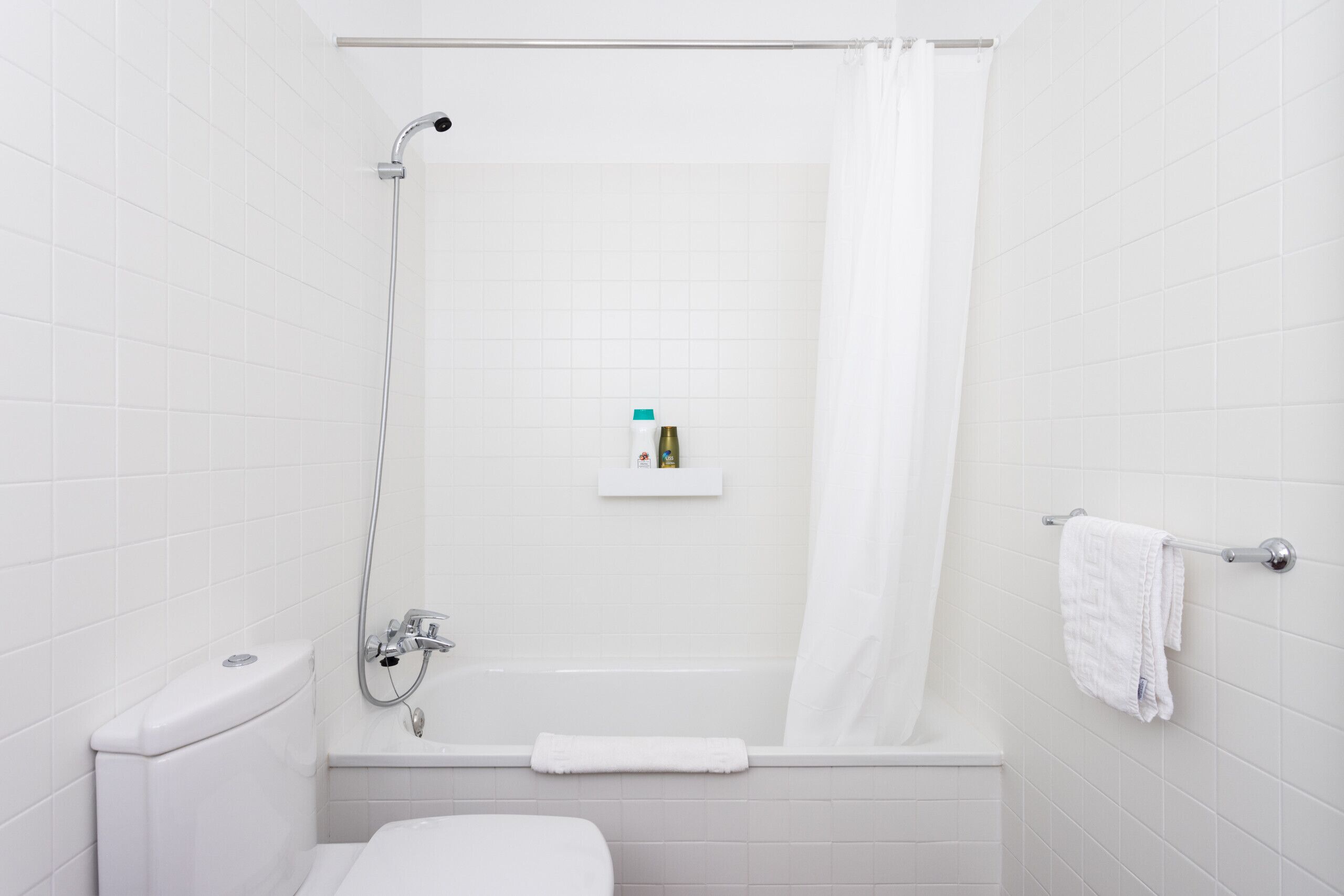 A bathroom with a bathtub, toilet, and a towel rack.