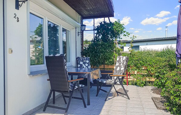 Relax on the patio surrounded by lush greenery, featuring a table and two chairs.