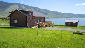 A wooden cabin with a porch, a smaller shed, and a lake in the background. - Henry`s Lake View Cabin + BBQ + Fire Pit + Decks! (Island Park)