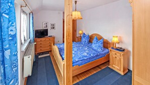 Ein Schlafzimmer mit einem hölzernen Himmelbett, zwei Nachttischen mit Lampen, einem Schminktisch und einem Heizkörper.