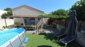 A backyard with a swimming pool, a covered patio area, and outdoor seating. - Vacances à 10 Minutes des Plages, Avec BBQ et Piscine (Châteauneuf les Martigues)