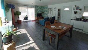 A spacious living room with a dining area, a kitchen, and a TV in the background. - Vacances à 10 Minutes des Plages, Avec BBQ et Piscine (Châteauneuf les Martigues)
