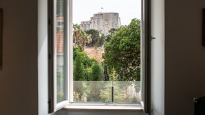 Ein Zimmer mit Eckfenster, das einen Blick auf ein historisches Gebäude und Grünflächen bietet.