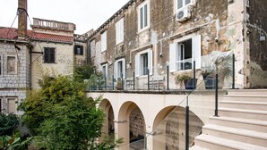 Ein historisches Gebäude mit Bogenstufen und einem Balkon mit Blick auf einen Garten.