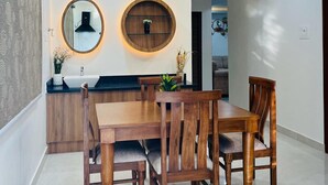 A modern dining area with a wooden table and chairs, a round mirror, and a ceiling fan. - Viola Suites (Hyderabad)