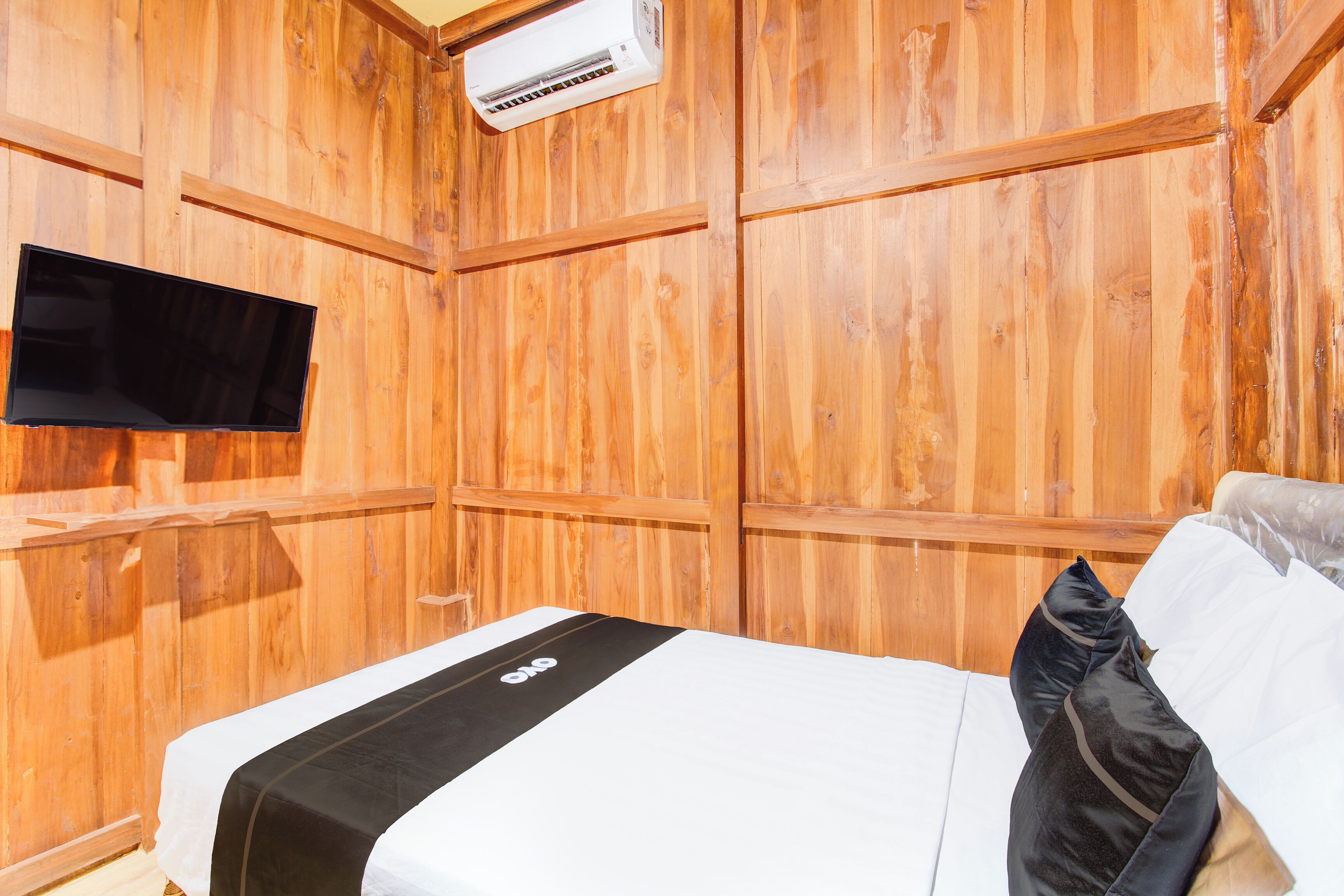 Een kamer met houten lambrisering, een bed, een flatscreen televisie en een airconditioning.