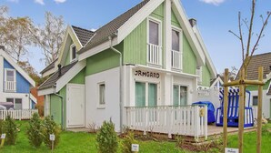 A two-story house with a green and white exterior, a balcony, and a sign reading "JRMGARD". - Ferienhaus Ostseebad Breege (Ostseebad Breege)