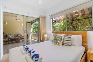 Habitación de hotel con cama, balcón y vista a palmeras.