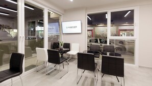 Ein moderner Autosaal mit einer großen Anzeige, die „COMFORT“ zeigt, und mehreren Sitzbereichen mit Stühlen und einem Tisch.