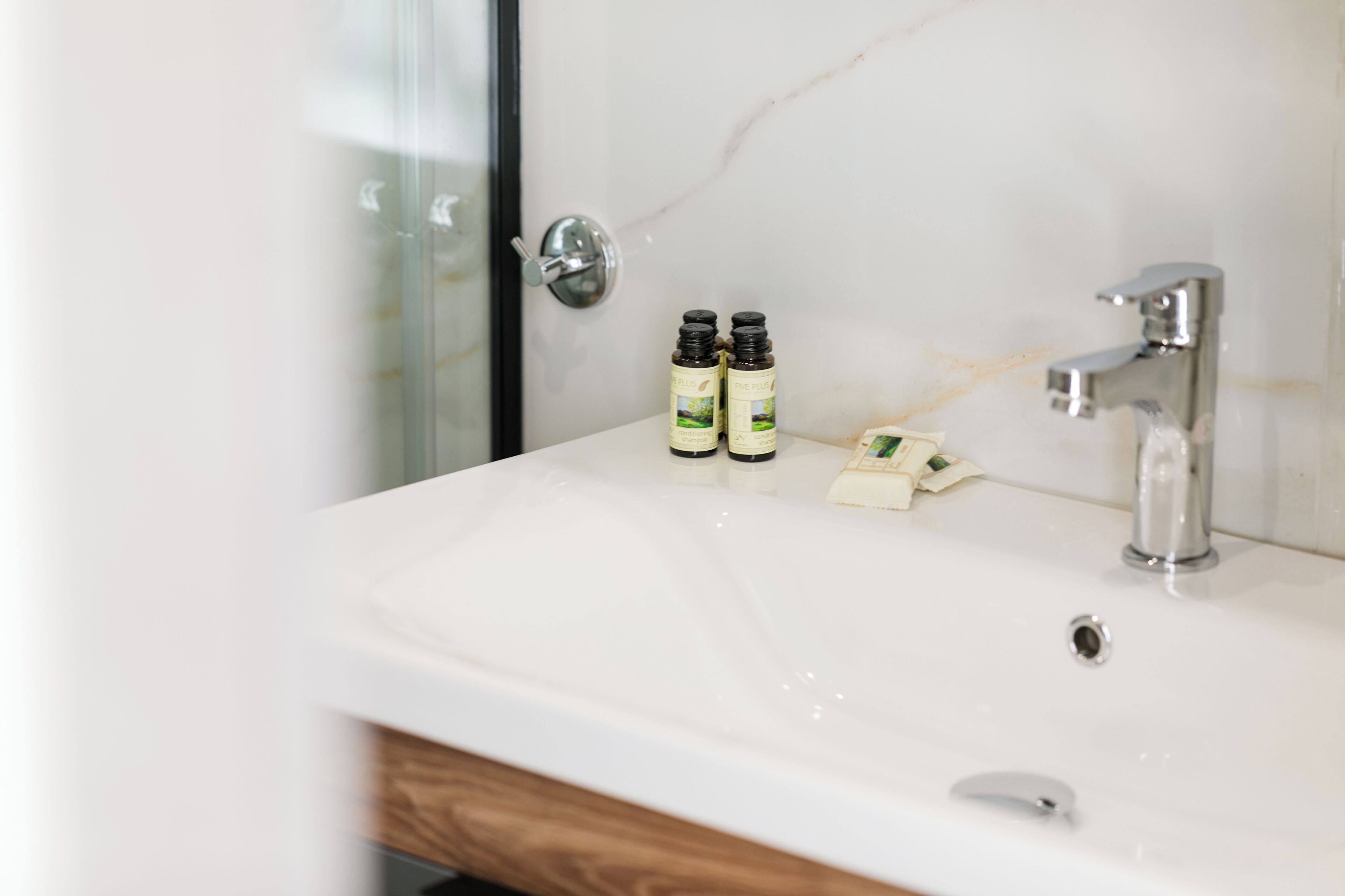 A bathroom with a white sink, two bottles of hand soap, and a shower area.