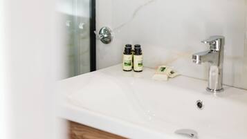 A bathroom with a white sink, two bottles of hand soap, and a shower area.