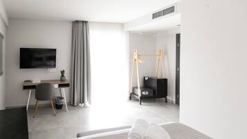 Une chambre d’hôtel moderne équipée d’un lit, d’un bureau, d’une chaise, d’une télévision et d’une petite plante.