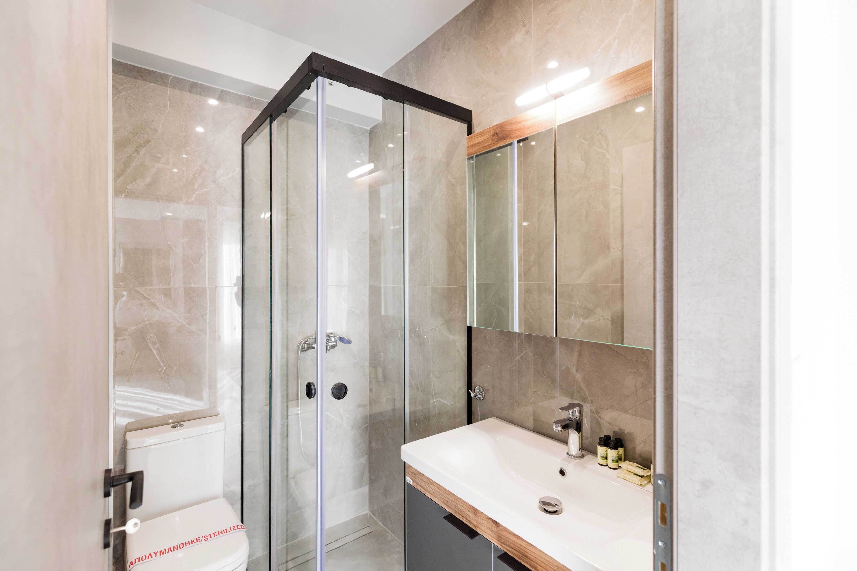 A modern bathroom with a glass shower enclosure, a white sink, and a mirror above the sink.