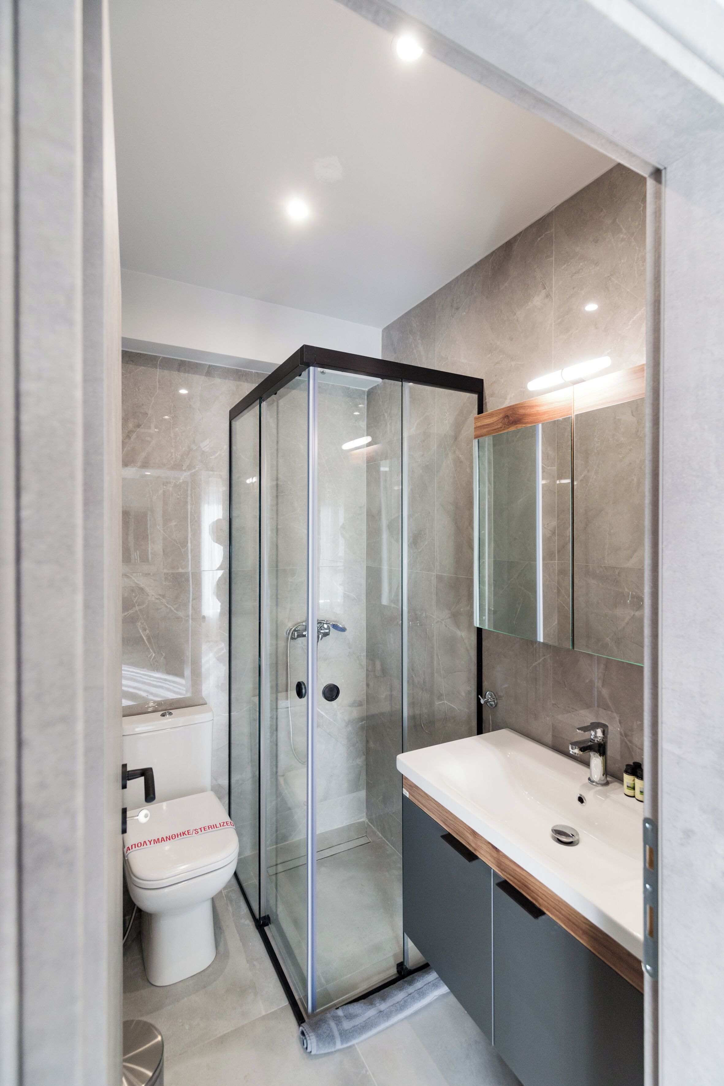 Un baño moderno con ducha envuelta en vidrio, inodoro blanco y tocador con espejo.
