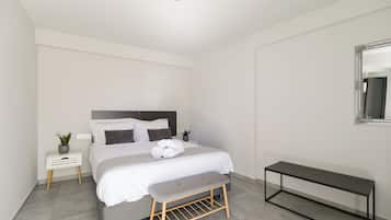 Een moderne slaapkamer met een bed, nachtkastjes, een bankje en een spiegel.