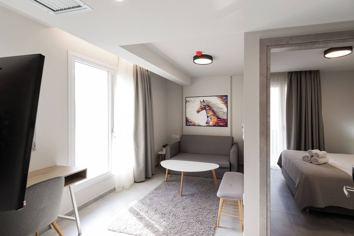 Een moderne hotelkamer met een bed, een bank, een tafeltje en een bureau.